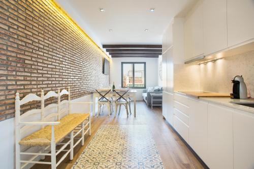 a kitchen with a brick wall and a table and chairs at Sweet Home Sitges BY BLAUSITGES in Sitges