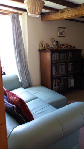 a living room with a blue couch and a window at Middle Woodbatch B&B in Bishops Castle