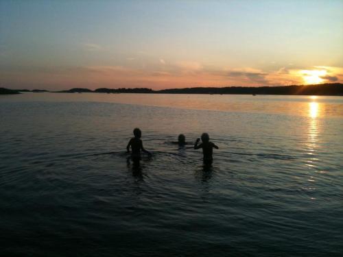 a group of people in the water at sunset at Hällestrand Seaview Apartment in Strömstad