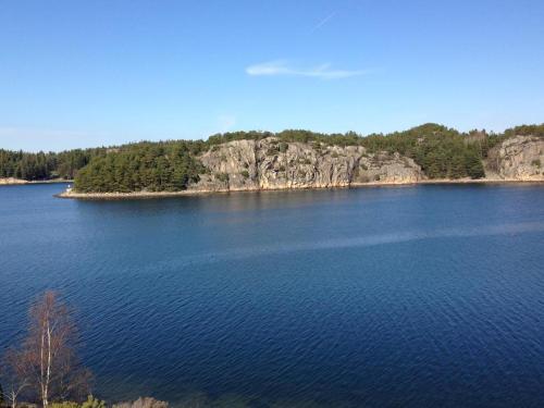 a large body of blue water with trees on the shore at Hällestrand Seaview Apartment in Strömstad