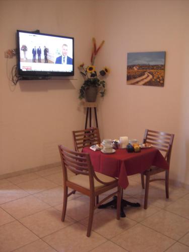 Un comedor con una mesa y un televisor en la pared. en Etna Inn, en Motta SantʼAnastasia