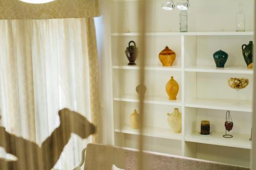 a room with shelves filled with vases and a window at La Casa dels Abeuradors in Gandesa
