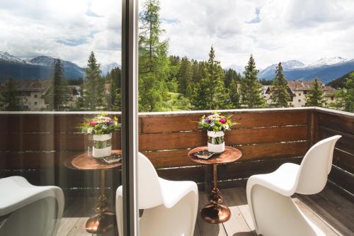 a balcony with tables and chairs and a view of mountains at Kurhaus Lenzerheide in Lenzerheide