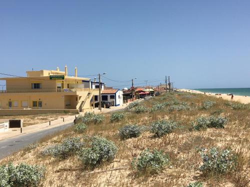 a beach with a building and the ocean at Apartamentos Barracuda in Faro