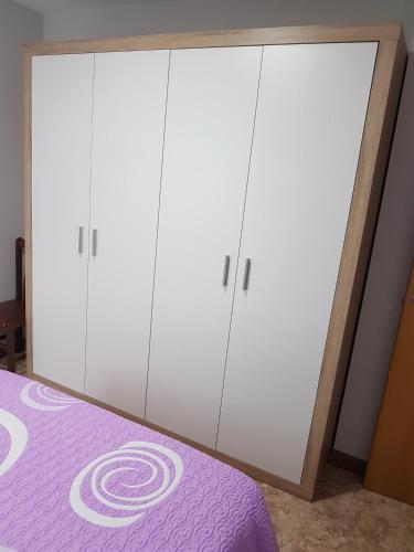 a bedroom with white cabinets and a purple bed at Apartamentos Rurales Los Solares in Mogro