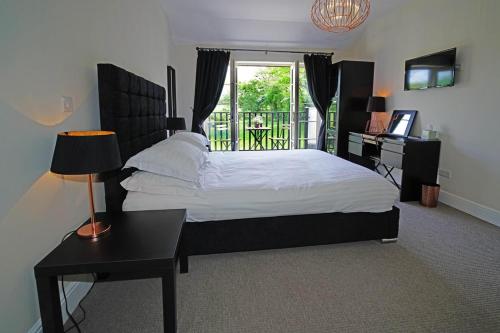 a bedroom with a bed and a desk and a window at Greyhound Hever in Edenbridge