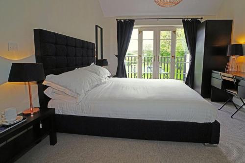a bedroom with a large bed and a desk and window at Greyhound Hever in Edenbridge