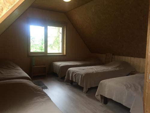 a attic room with three beds and a window at Metsaääre Accommodation in Uulu