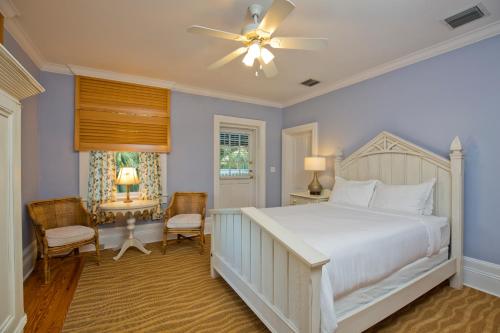 a bedroom with a white bed and a ceiling fan at Weatherstation Inn Circa 1911 in Key West