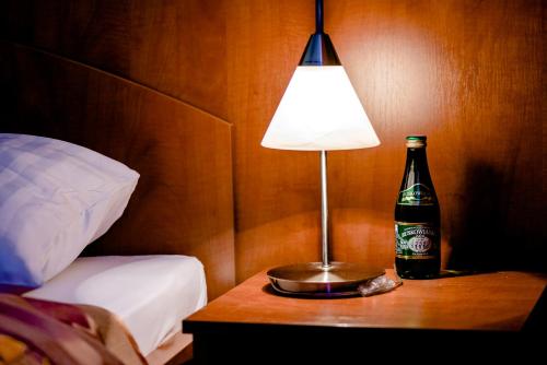 a bottle of beer and a lamp on a table next to a bed at Hotel Stal in Stalowa Wola