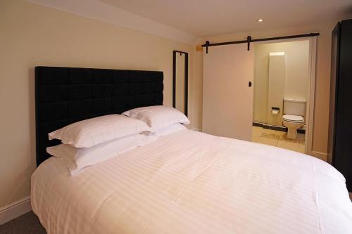 a bedroom with a large white bed with a black headboard at Greyhound Hever in Edenbridge