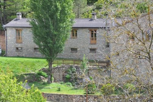 an old stone house with a fence and trees at Apartamento Molí de Fòrnols in Fornols