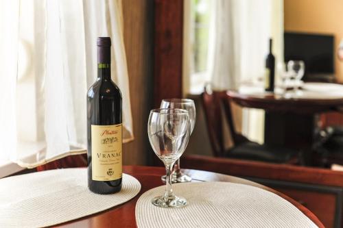 a bottle of wine and a wine glass on a table at Villa Dolphin Apartments in Petrovac na Moru