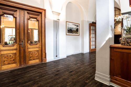 an empty hallway with wooden doors and wood floors at Kurhaus Lenzerheide in Lenzerheide