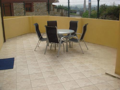 a patio with a table and chairs and a yellow wall at Apartamentos Rurales Los Solares in Mogro