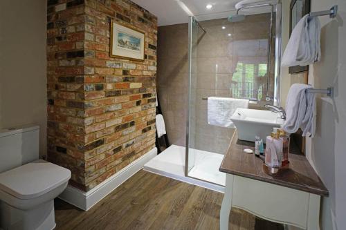 a bathroom with a sink and a brick wall at Greyhound Hever in Edenbridge