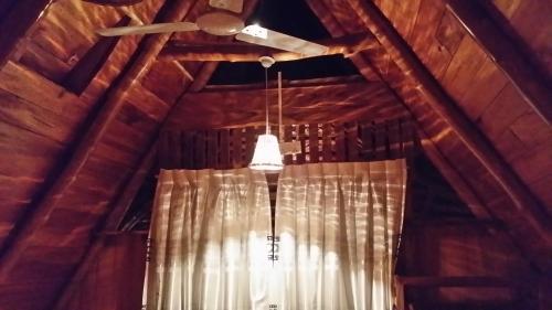 a ceiling with a ceiling fan and a window with a light at Lizard Safari Lodge in Udawalawe