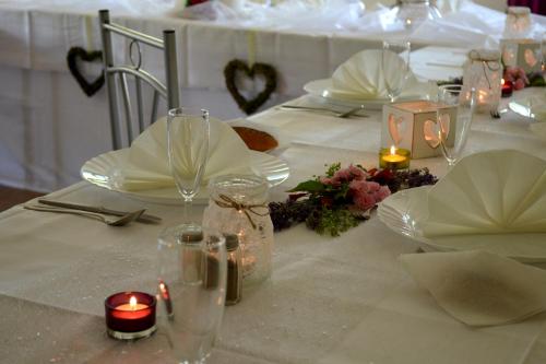 a table with a white table cloth with candles and glasses at Ubytování - U nás doma in Orličky