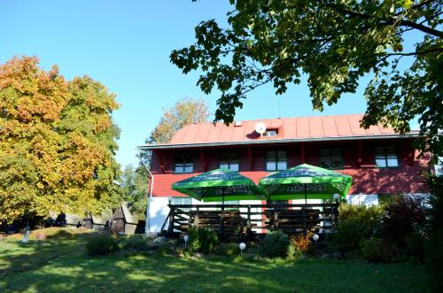 a building with two green umbrellas in front of it at Ubytování - U nás doma in Orličky