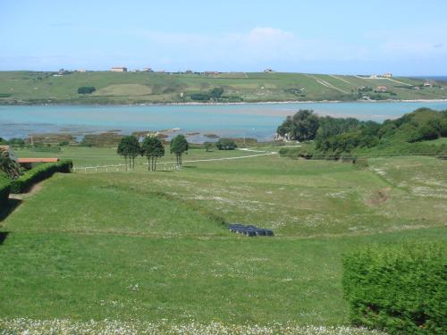 a green field with a view of a body of water at Apartamentos Rurales Los Solares in Mogro
