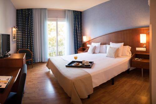 Habitación de hotel con cama grande y bandeja. en Hotel Delfín, en Tossa de Mar