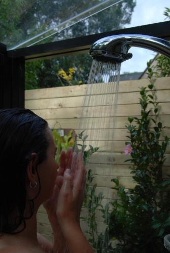 a woman is washing her hands under a shower at Witches Falls Cottages in Mount Tamborine