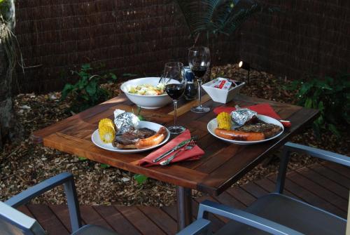 a wooden table with plates of food and glasses of wine at Witches Falls Cottages in Mount Tamborine