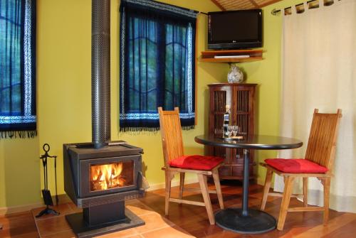 a living room with a stove and a table and chairs at Witches Falls Cottages in Mount Tamborine