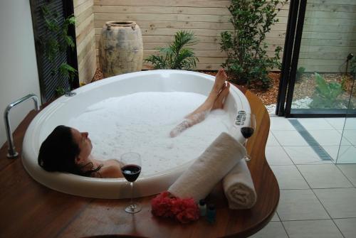 a woman laying in a bath tub with a glass of wine at Witches Falls Cottages in Mount Tamborine