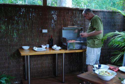 a man standing next to a table with a grill at Witches Falls Cottages in Mount Tamborine