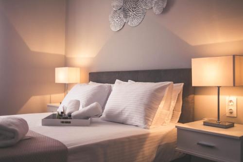 a bedroom with a bed with white pillows and two lamps at Teatro Deluxe Rooms in Kato Rodini