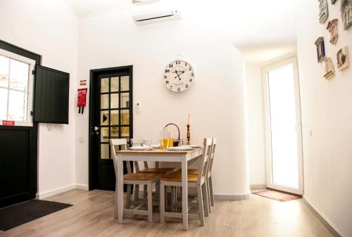 a dining room with a table and a clock on the wall at Villa Marquês near Tejo River in Cruz Quebrada