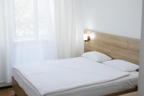 a white bed with two pillows and a window at Sakura Inn in Fergana