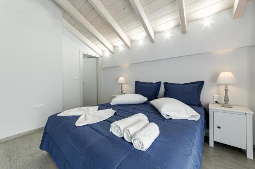 a bedroom with a blue bed with towels on it at Liberte Maisonettes in Parga