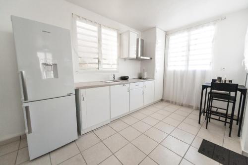 a white kitchen with a refrigerator and a table at Locastudio - Carambole in Sainte-Anne