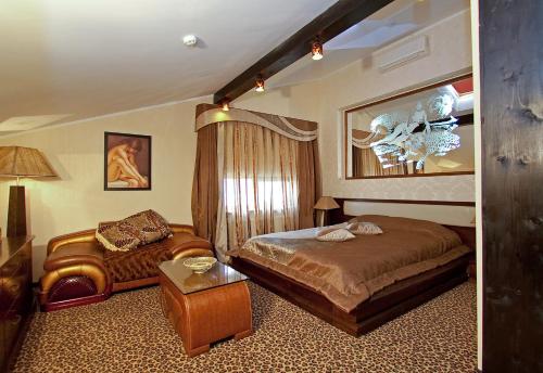 a bedroom with a bed and a chair in it at Deluxe Hotel Kupava in Lviv