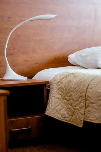 a white lamp on a nightstand next to a bed at Hotel Stal in Stalowa Wola