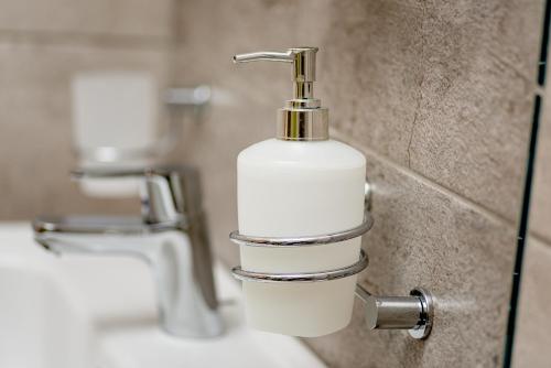 a bathroom with a white soap dispenser on a wall at Hotel Stal in Stalowa Wola