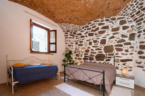 オロゼーイにあるResidenza Maria Antonia - Historical Suiteの石壁のベッドルーム1室(ベッド2台付)