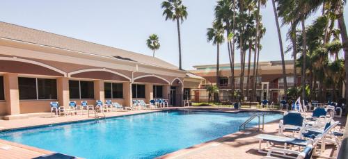 a large swimming pool with chairs and palm trees at La Copa Hotel in McAllen