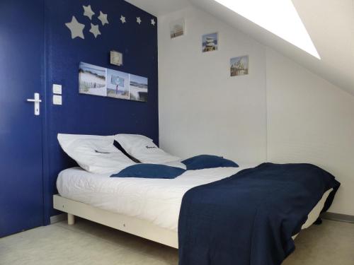 uma cama num quarto com uma parede azul em L'hirondelle em Cancale
