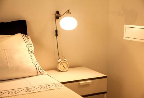 a bedroom with a bed with a lamp and a clock on a nightstand at Villa Marquês near Tejo River in Cruz Quebrada