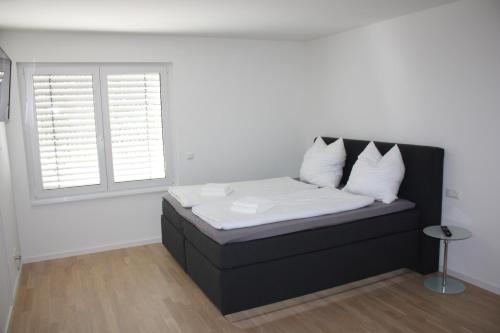 Cama negra con sábanas blancas y almohadas en una habitación en Salvatorferienwohnung, en Schwäbisch Gmünd