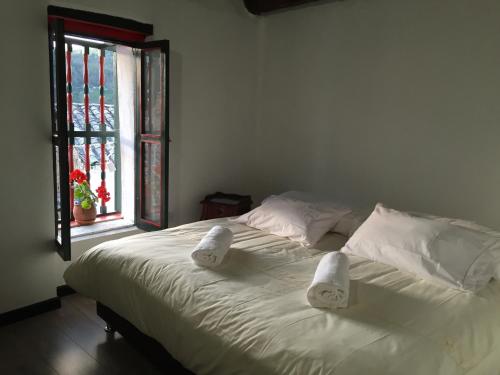 a bed with white sheets and pillows and a window at Hotel Otti Colonial in Monguí