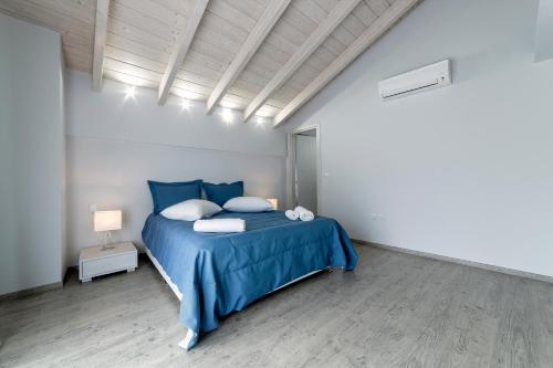 a bedroom with a blue bed in a white room at Liberte Maisonettes in Parga