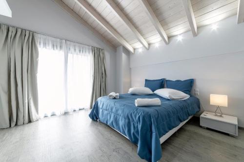a bedroom with a blue bed and a large window at Liberte Maisonettes in Parga