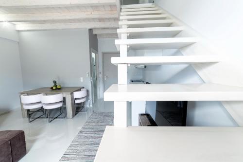 a white staircase in a living room with a table at Liberte Maisonettes in Parga