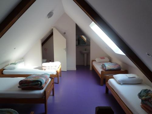 a attic room with four beds and a window at Gite de la Croix du Hêtre in Hambers