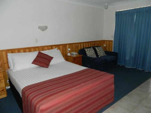 a hotel room with a bed and a chair at Twin Towns Motel in Tweed Heads
