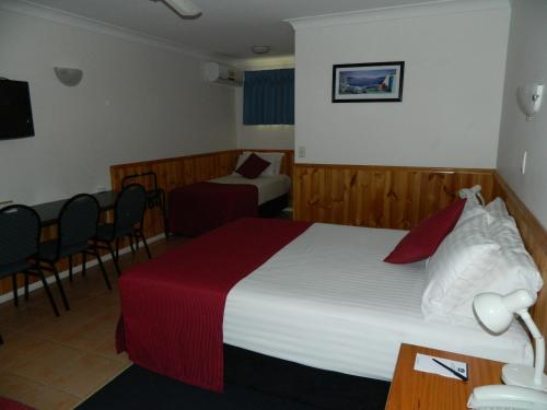 a hotel room with a large bed and a chair at Twin Towns Motel in Tweed Heads